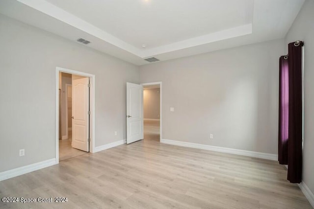 unfurnished bedroom featuring light hardwood / wood-style flooring and a raised ceiling