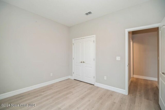 unfurnished bedroom with light wood-type flooring and a closet