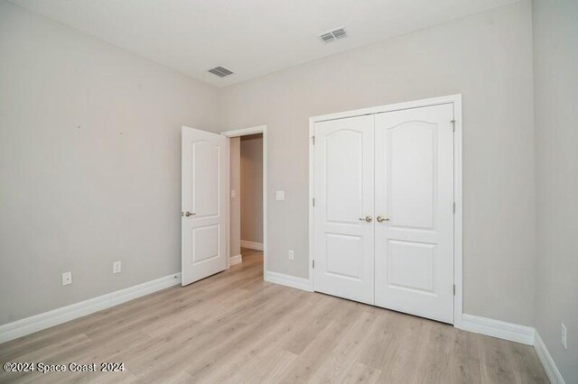 unfurnished bedroom featuring light hardwood / wood-style flooring and a closet