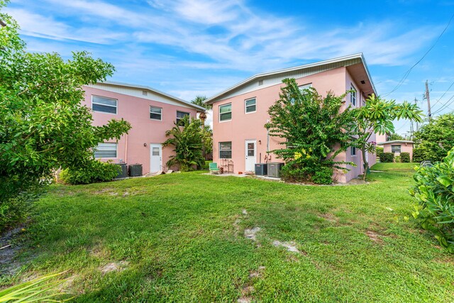 rear view of property with central AC and a yard