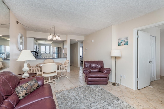 living room featuring an inviting chandelier, sink, light tile patterned floors, and a textured ceiling