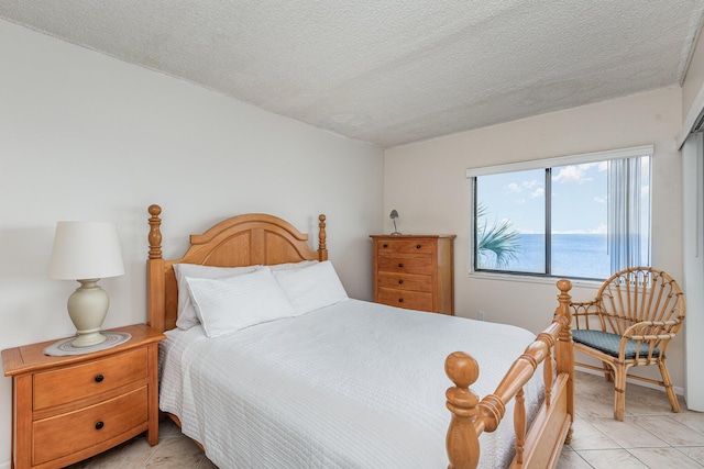 tiled bedroom featuring a water view and a textured ceiling