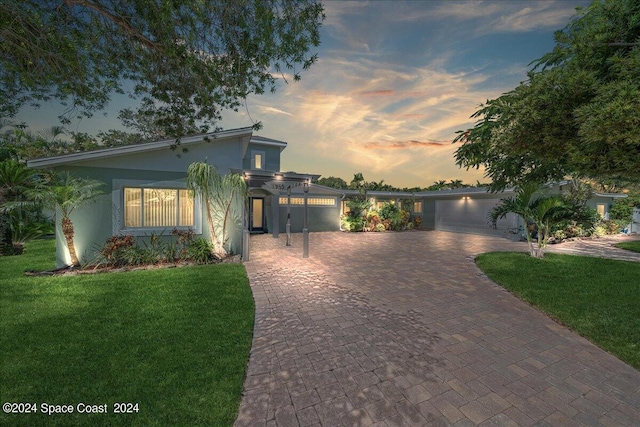 view of front facade with a garage, a water view, and a lawn