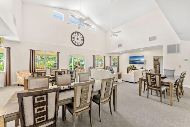 dining room with ceiling fan, light colored carpet, and high vaulted ceiling