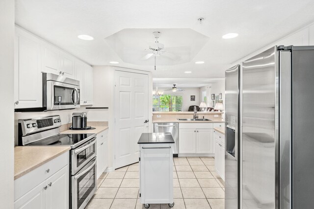 kitchen with a kitchen island, white cabinetry, sink, light tile patterned floors, and stainless steel appliances