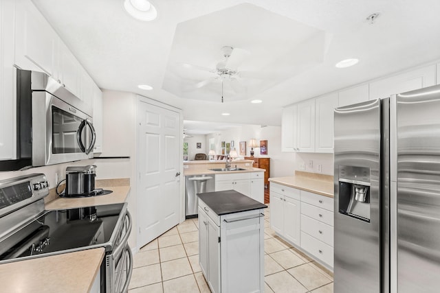 kitchen with sink, a center island, a raised ceiling, stainless steel appliances, and white cabinets