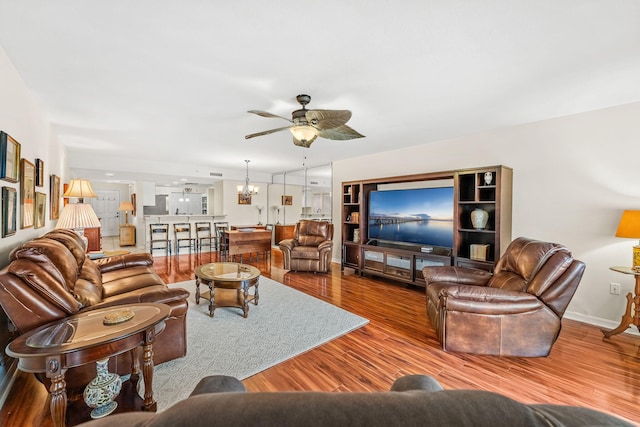 living room featuring ceiling fan with notable chandelier and light wood-type flooring