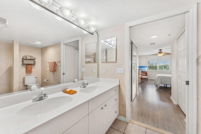 bathroom with tile patterned floors, toilet, a textured ceiling, vanity, and ceiling fan