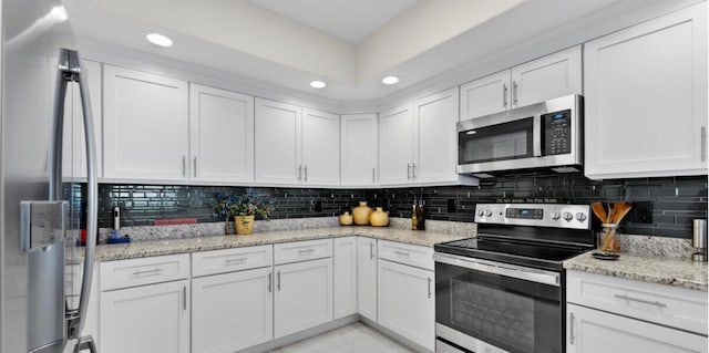 kitchen featuring decorative backsplash, light stone countertops, stainless steel appliances, and white cabinetry