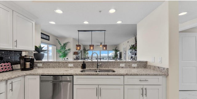 kitchen featuring dishwasher, sink, light stone counters, and a wealth of natural light