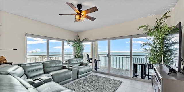 tiled living room featuring ceiling fan and a water view