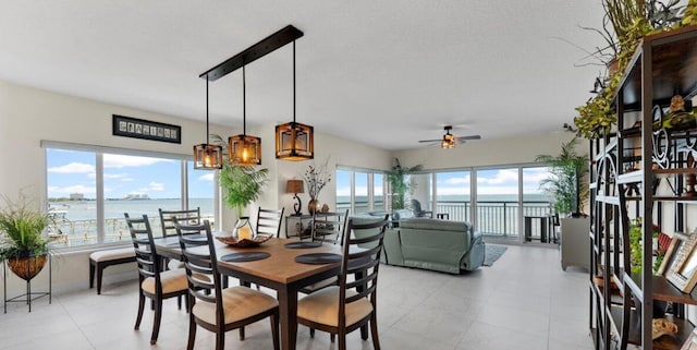 dining space featuring light tile patterned flooring, plenty of natural light, and a water view