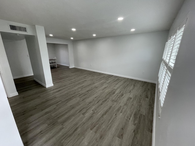 spare room featuring baseboards, dark wood finished floors, visible vents, and recessed lighting