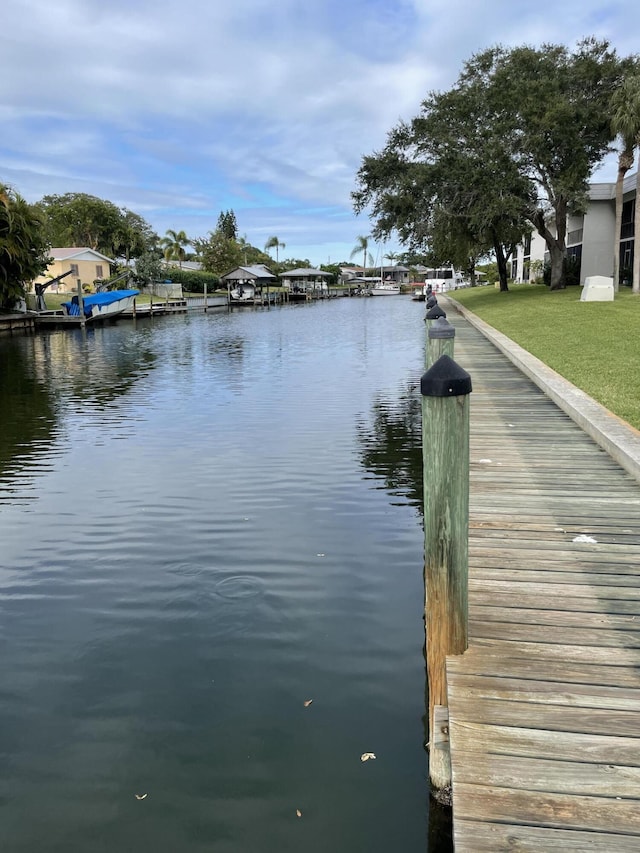 view of dock with a water view and a yard