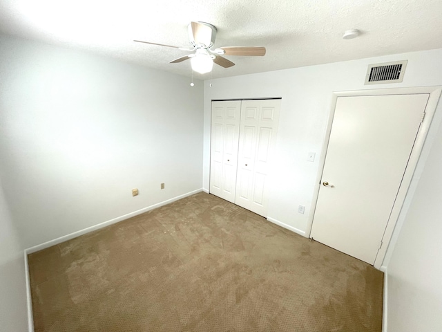 unfurnished bedroom with ceiling fan, carpet floors, a closet, and a textured ceiling