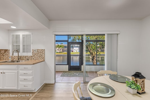 dining room featuring a water view, baseboards, and light wood finished floors