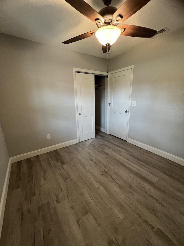 unfurnished bedroom featuring dark wood-type flooring, ceiling fan, and a closet