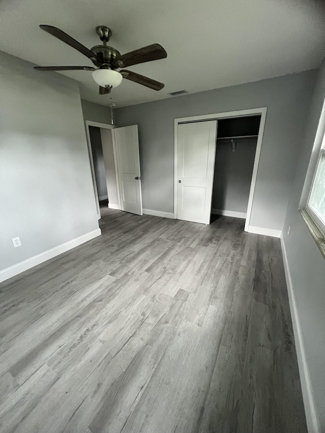 unfurnished bedroom featuring wood-type flooring, ceiling fan, and a closet