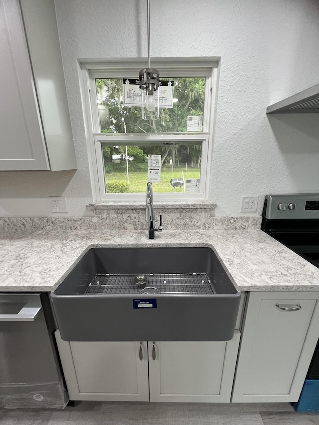 kitchen featuring range hood, sink, a notable chandelier, and stainless steel appliances