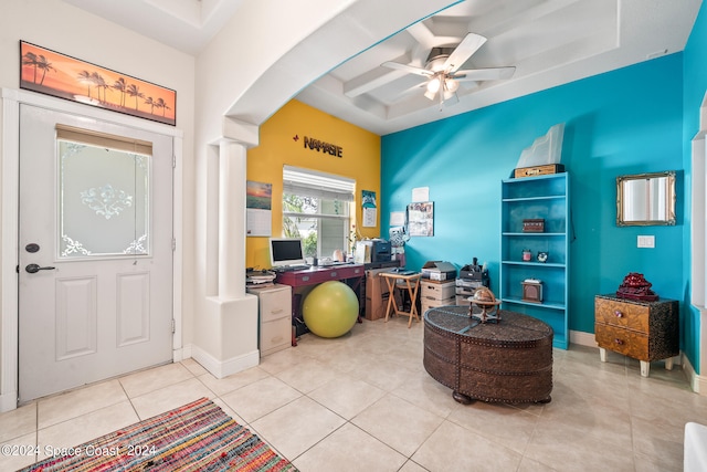 foyer entrance featuring ceiling fan, a raised ceiling, decorative columns, and light tile patterned flooring