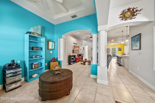 sitting room featuring ceiling fan, a raised ceiling, light tile patterned flooring, and ornate columns