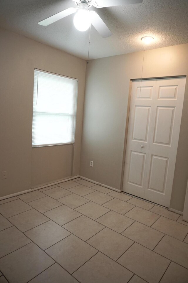 interior space with a textured ceiling and ceiling fan