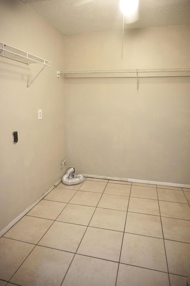 washroom featuring a textured ceiling, light tile patterned floors, and hookup for an electric dryer