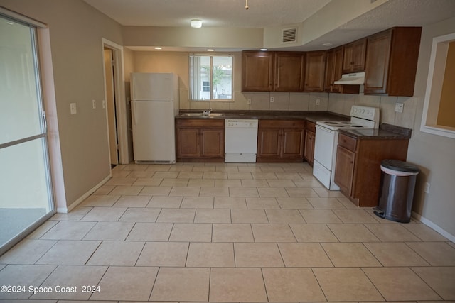 kitchen featuring white appliances, light tile patterned floors, and decorative backsplash