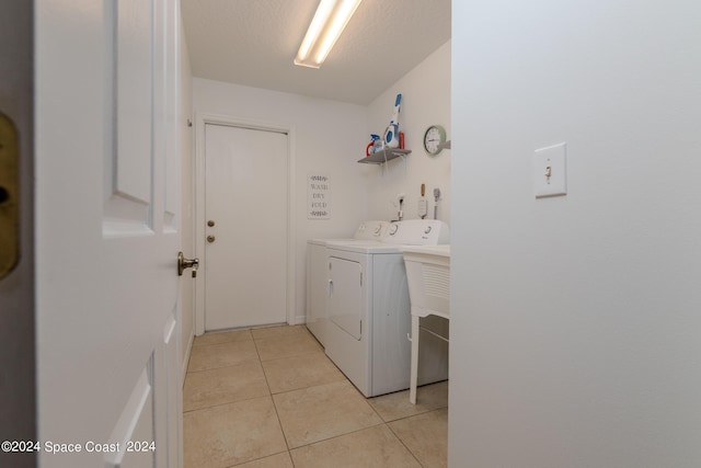 clothes washing area with washer and dryer and light tile patterned floors