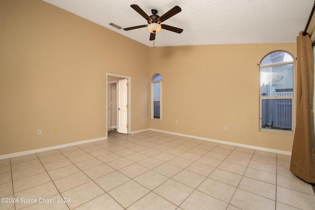 tiled empty room featuring a textured ceiling, ceiling fan, and high vaulted ceiling