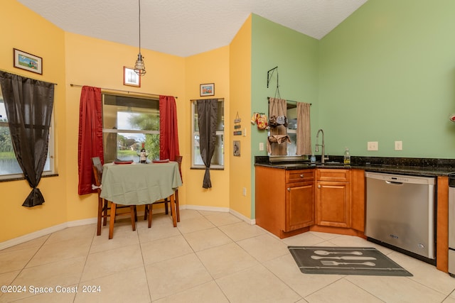 kitchen featuring sink, stainless steel dishwasher, light tile patterned flooring, pendant lighting, and a textured ceiling