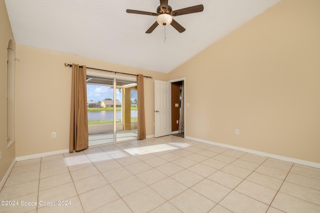 tiled spare room featuring lofted ceiling, a water view, and ceiling fan