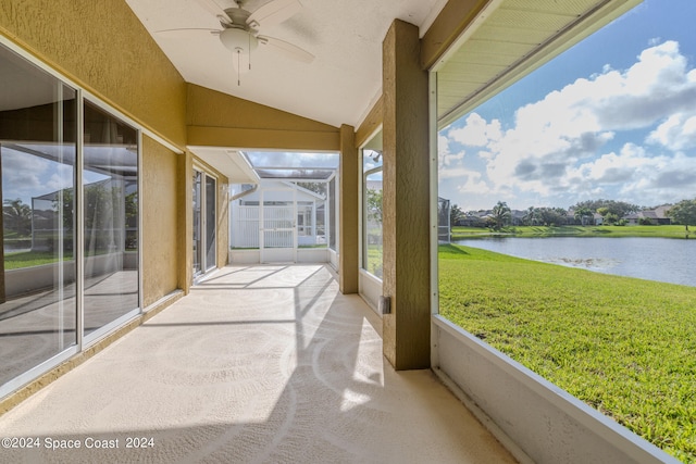 sunroom with a healthy amount of sunlight, ceiling fan, and a water view