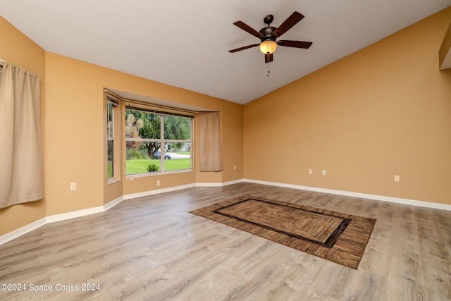 empty room with light wood-type flooring, vaulted ceiling, and ceiling fan