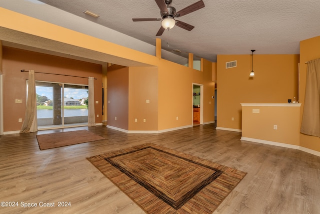 unfurnished living room featuring high vaulted ceiling, ceiling fan, a textured ceiling, and light hardwood / wood-style flooring