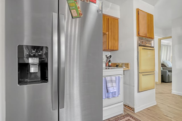 kitchen with stove, multiple ovens, light hardwood / wood-style flooring, and stainless steel fridge with ice dispenser