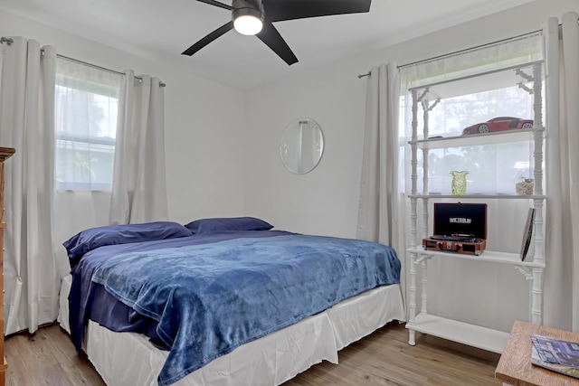 bedroom featuring ceiling fan, multiple windows, and hardwood / wood-style flooring