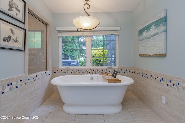 bathroom featuring tile walls, a tub to relax in, and tile patterned flooring