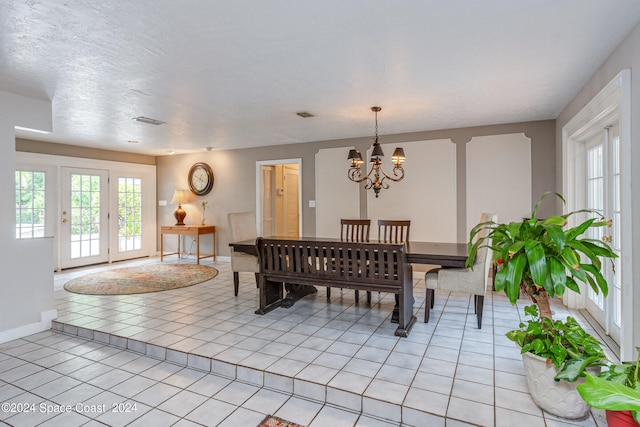 dining room featuring a textured ceiling, an inviting chandelier, and light tile patterned floors