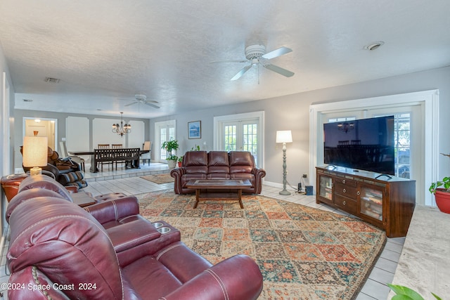 living room with a textured ceiling, light tile patterned floors, and ceiling fan with notable chandelier