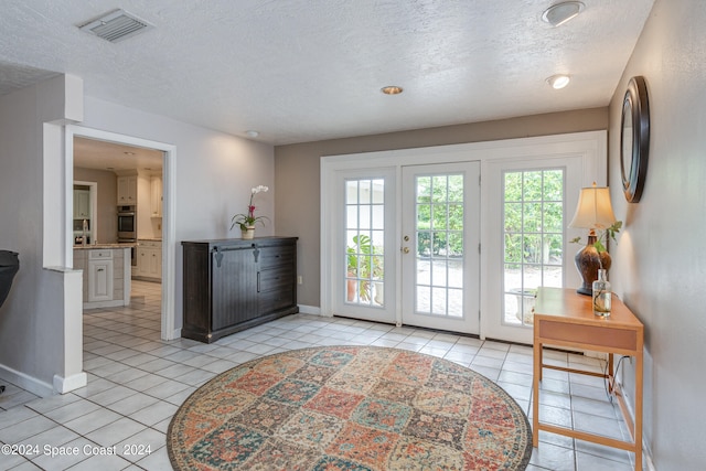 doorway to outside featuring french doors, a textured ceiling, and light tile patterned floors