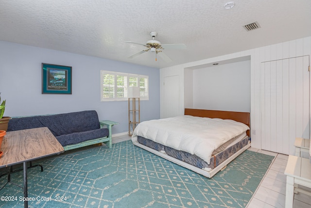 bedroom with ceiling fan, tile patterned floors, and a textured ceiling