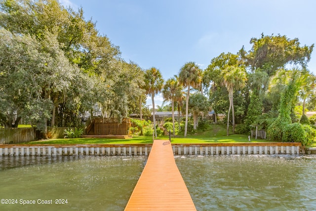 view of dock featuring a lawn and a water view