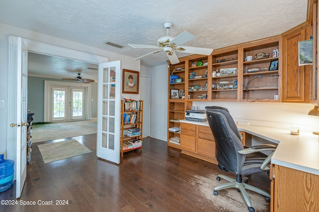 unfurnished office featuring french doors, built in desk, a textured ceiling, ceiling fan, and dark wood-type flooring