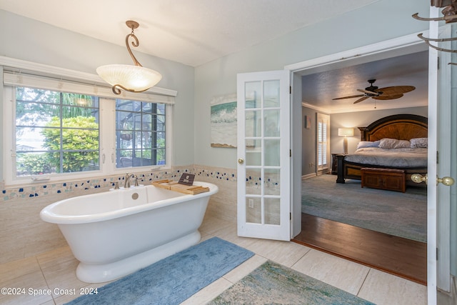 bathroom with ceiling fan, wood-type flooring, a washtub, and tile walls