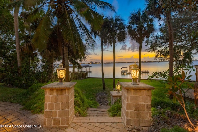 patio terrace at dusk with a water view and a yard