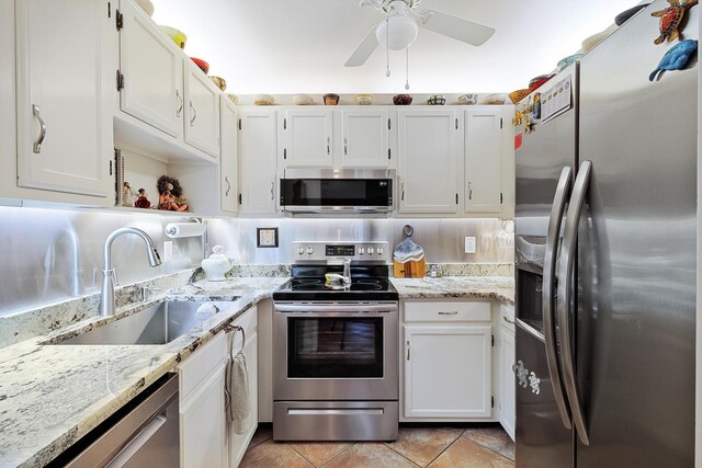 kitchen featuring sink, white cabinets, light tile patterned floors, light stone counters, and stainless steel appliances