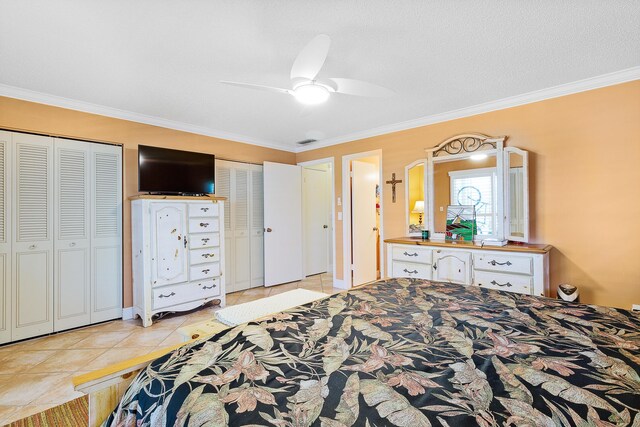 tiled bedroom featuring crown molding, two closets, a textured ceiling, and ceiling fan