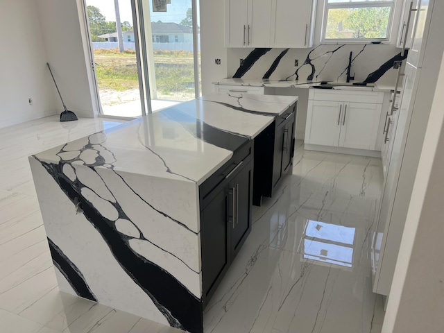 kitchen with light stone counters, backsplash, and white cabinets