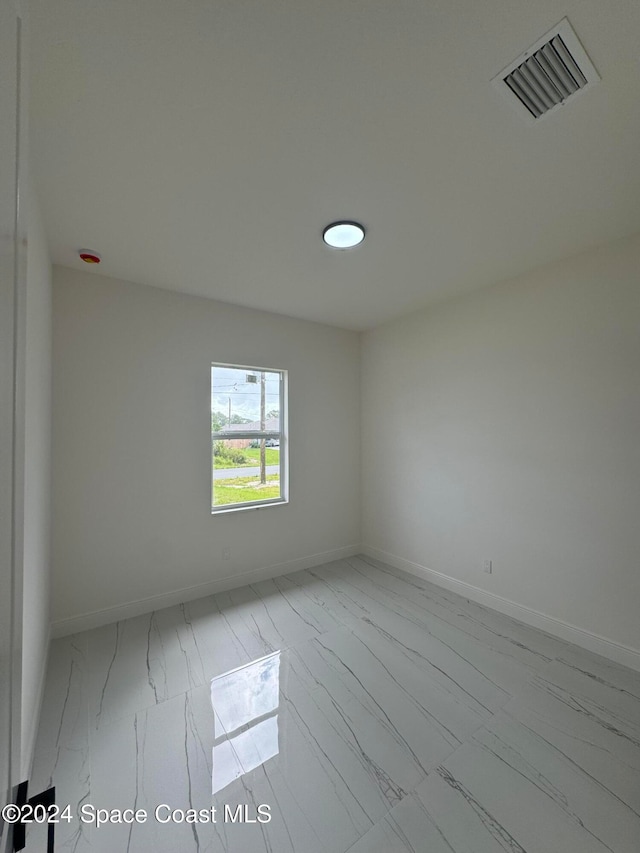 spare room featuring marble finish floor, visible vents, and baseboards